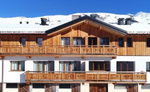 ein großes Holzgebäude mit Schnee auf dem Dach in der Unterkunft Odalys Chalet D'Alice in Les Menuires