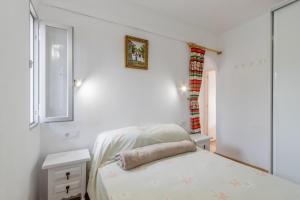ein weißes Zimmer mit einem Bett und einem Fenster in der Unterkunft Retirosol Bungalow in Denia