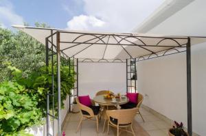 a patio with a table and chairs under a white umbrella at Apartment & Room Lady O in Dubrovnik +23 photos