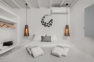 a white bedroom with a bed with two pillows at Xerolithos Natural Living in Naxos Chora +114 photos