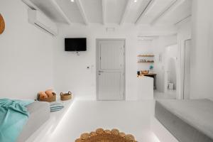 a white living room with a couch and a tv at Xerolithos Natural Living in Naxos Chora