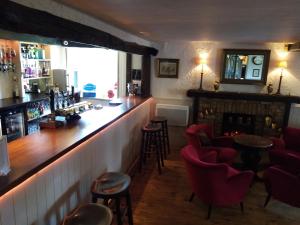 a bar in a pub with red chairs and a fireplace at The Sibson Inn Hotel in Water Newton