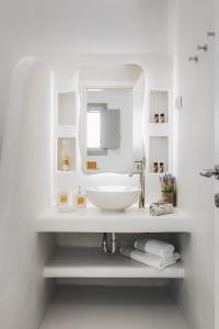 a white bathroom with a sink and a mirror at Xerolithos Natural Living in Naxos Chora
