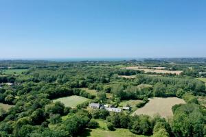 une vue aérienne sur une ferme plantée d'arbres et de champs dans l'établissement Manoir de l'Isle, à Ploumilliau