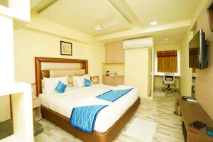 a bedroom with a large bed and a desk at Hotel SK Riverfront in Vijayawāda