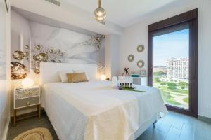 a white bedroom with a large bed and a large window at Teatinos Sky Garden I - CT 164 in Málaga