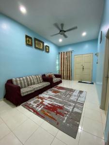 a living room with a couch and a rug at illiy's homestay in Tangga Batu