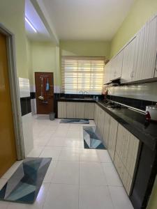 a large kitchen with white tile flooring and a window at illiy's homestay in Tangga Batu