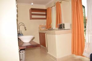 y baño con lavabo y microondas. en Stylish 2BR with Wi-Fi and secure parking, en Kakamega