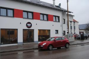 a red car parked in front of a building at B&S Hotel in Weißenhorn