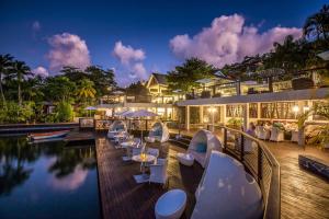 Un complejo con piscina, mesas y sillas. en Superb Split Level Waterside Apt, Marigot Bay, St Lucia WI, en Castries