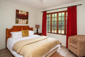 um quarto com uma cama, uma cadeira e uma janela em Whispering Pines Country Estate em Magaliesburg