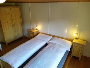 two beds in a room with two lights on the wall at Gasthaus Meinradsberg in Einsiedeln