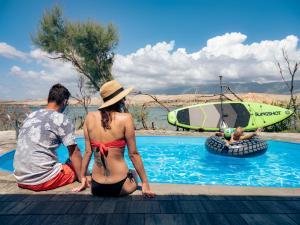 a man and a woman sitting next to a swimming pool at Terra Park SpiritoS in Kolan