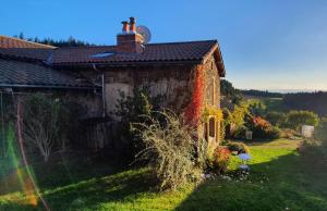 uma casa velha com um arco-íris em frente em Cottage panoramique em Champagnac-le-Vieux