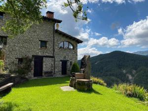 an old stone house on a green lawn with mountains in the background at Mas merolla casa para descanso familiar in Gombreny