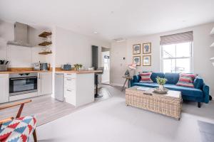 a living room with a blue couch and a kitchen at Pebble View in Aldeburgh