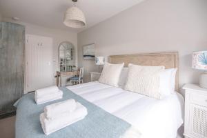 a bedroom with a large white bed with towels on it at Pebble View in Aldeburgh