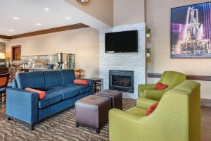 Comfort Inn & Suites في سينسيناتي: غرفة معيشة مع أريكة وكرسيين ومدفأة
