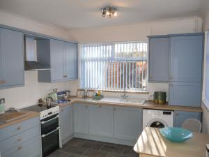 a kitchen with blue cabinets and a sink and a window at Anchor Cottage in Cleethorpes