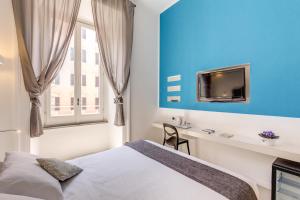 - une chambre avec un lit et un bureau avec une télévision dans l'établissement Manin Suites LT, à Rome