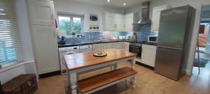 a kitchen with a wooden table and a refrigerator at Kindly Light Beach House in Porthmadog