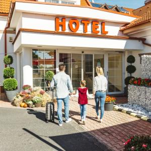 a family walking in front of a hotel at Hotel Paprika in Hegyeshalom