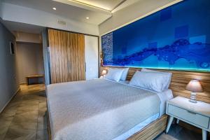 a bedroom with a large bed with a blue painting on the wall at Island Boutique Hotel in Rhodes Town