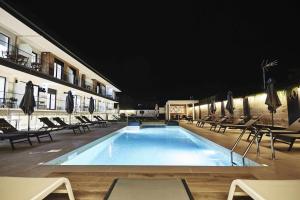 una piscina por la noche con sillas y sombrillas en Viviendas Vacacionales ENTREPLAYAS Foz, en Foz
