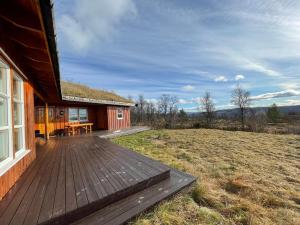 a house with a wooden deck next to a field at Magnesplass - Dagalifjell in Dagali