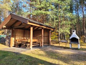 a wooden pavilion with a grill in the woods at Kaszubskie Zacisze dom nad jeziorem, sauna, balia ogrodowa in Lipusz
