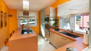 eine Küche mit orangefarbenen Wänden und einer großen Insel in der Unterkunft Hospedium Galitrips Vila Maruja Corme in Corme-Puerto