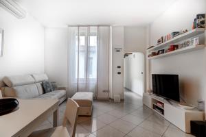 Biały salon z kanapą i telewizorem w obiekcie Appartamento comodo nei pressi dell'Archiginnasio by Wonderful Italy w Bolonii