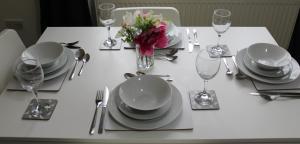 Clover Apartments في Hadleigh: طاولة بيضاء عليها صحون و فضيات و ورد