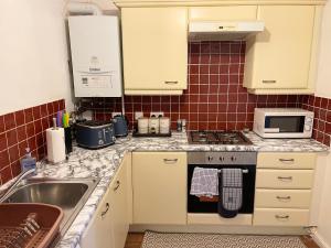 Clover Apartments في Hadleigh: مطبخ مع مغسلة وموقد فرن علوي