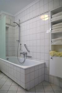 ein weißes Bad mit einer Badewanne und einer Dusche in der Unterkunft K & R Appartements Binz in Binz