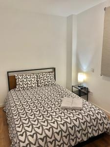 1 dormitorio con 1 cama con edredón blanco y negro en Centro Metro Usera 01, en Madrid