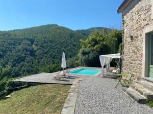a house with a swimming pool next to a mountain at Encanto Di Arlia in Fivizzano