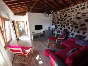 a living room with a red couch and a stone wall at Casa Sol in Hermigua
