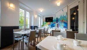 a restaurant with white tables and chairs and a painting at Hôtel du Parc Montparnasse in Paris