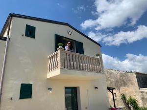 a woman is looking out of a window on a balcony at Agriturismoeloropizzuta in Noto Marina