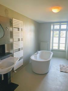ein großes weißes Badezimmer mit einer Badewanne und einem Waschbecken in der Unterkunft Château de la Combe in La Celle