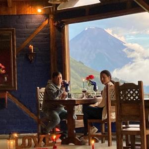 un hombre y una mujer sentados en una mesa con una montaña en La Montaña Restaurante Mirador, en Patate