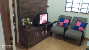 a living room with two chairs and a television at Casa de Temporada Serra da Canastra - São Roque de Minas in São Roque de Minas
