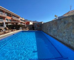 una piscina de agua azul y una pared de piedra en Hotel La Aldea Suites, en San Nicolás