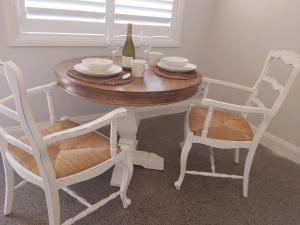 a table with two chairs and a bottle of wine at Chez Vous French Farmhouse Villa 3! in Pokolbin