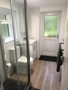 a bathroom with a toilet and a glass door at Luxury Log Cabin with Outdoor Wood Fired Hot Tub & Pizza Oven in Ribchester