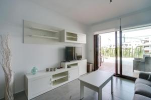 a white living room with a tv and a table at Apartment Chendula in San Juan de los Terreros