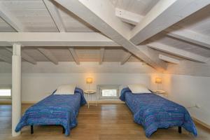 two beds in a room with wooden floors at Villino Ermione in Marina di Pisa