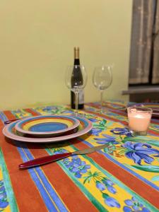 una mesa con un colorido mantel con platos y copas de vino en Un tocco provenzale a Savigliano, en Savigliano
